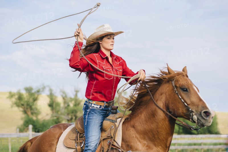 Caucasian cowgirl throwing lasso on horseback