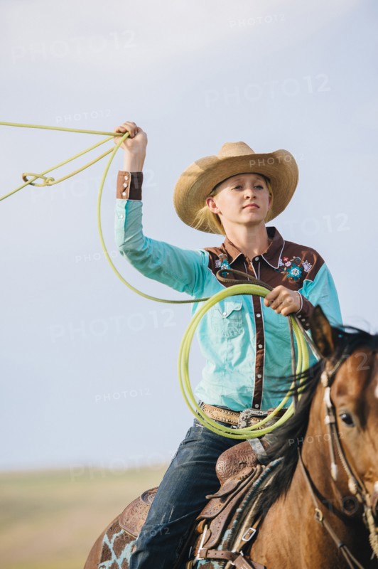 Caucasian cowgirl throwing lasso on horseback