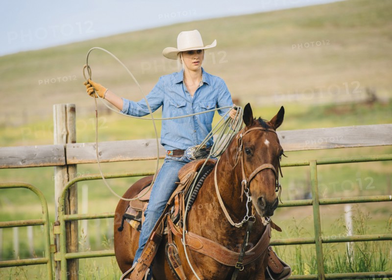 Caucasian cowgirl throwing lasso on horseback