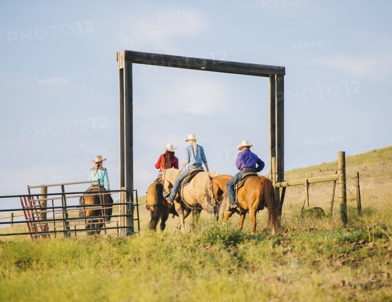 Cowboy and cowgirls riding horseback on ranch