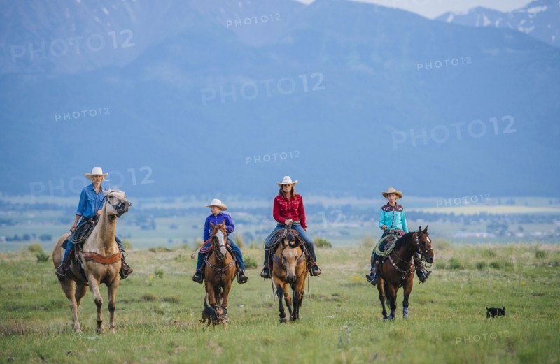 Cowboy and cowgirls riding horseback on ranch
