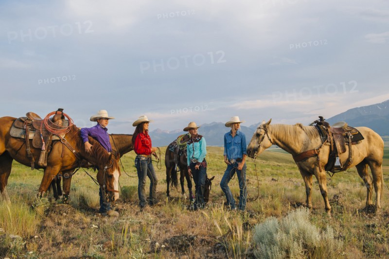 Cowboy and cowgirls with horses on ranch