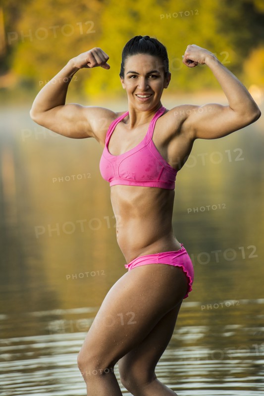 Mixed Race woman flexing muscles in lake
