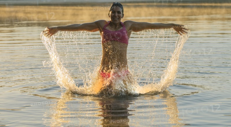 Mixed Race woman splashing in lake