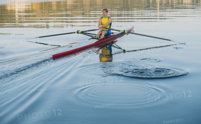 Caucasian man rowing on lake