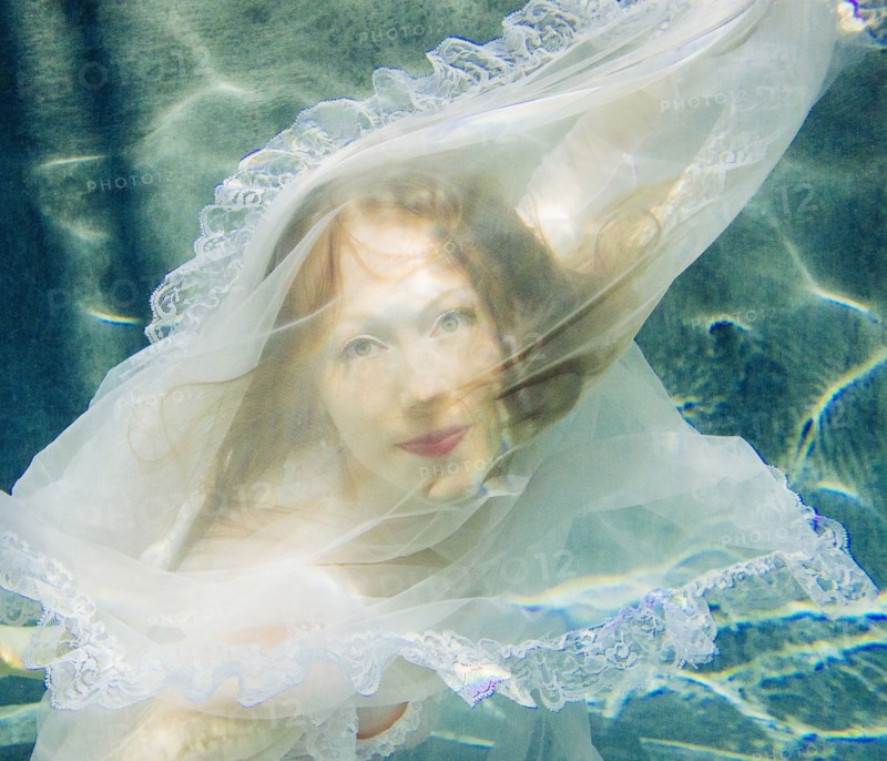 Caucasian woman wearing dress swimming underwater