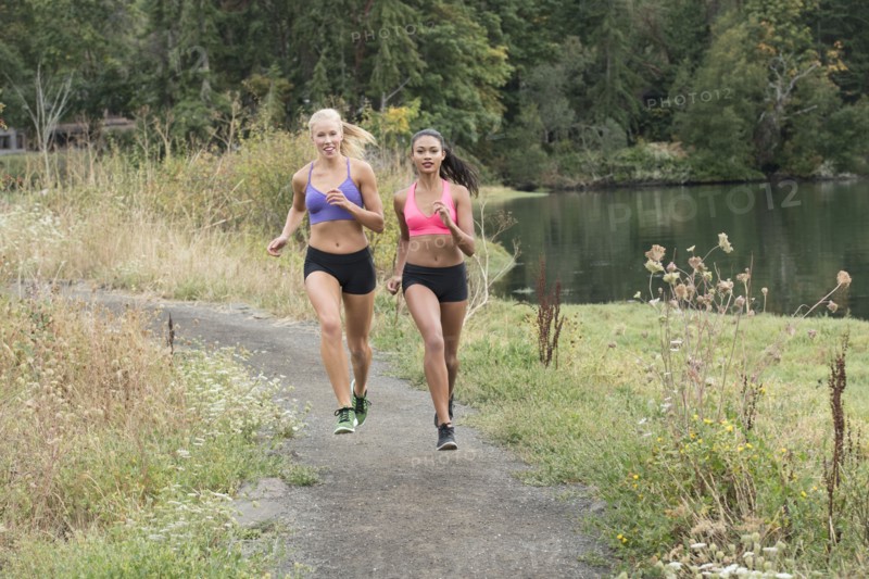 Women running on park path near lake