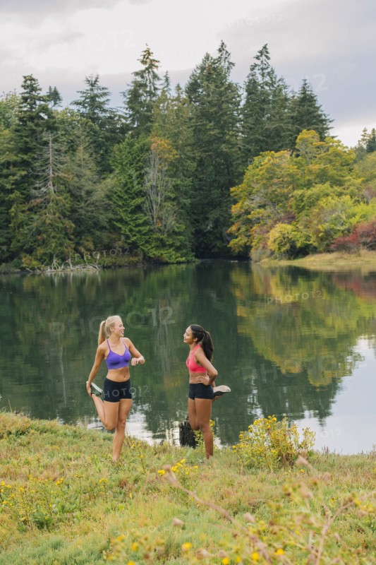 Women stretching legs near lake