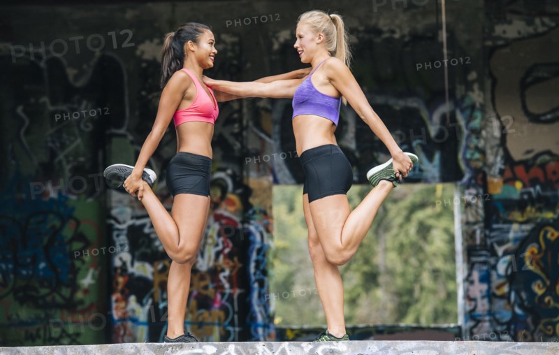 Women stretching legs near graffiti
