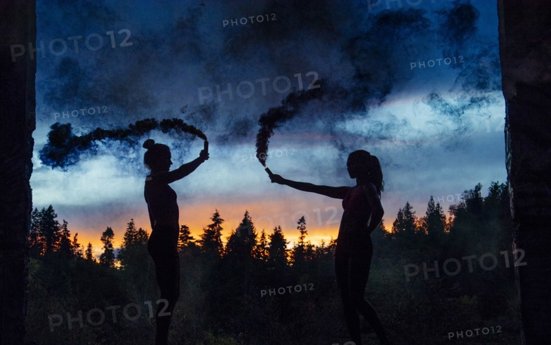 Silhouette of women holding smoking flares