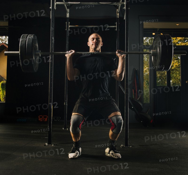 Man lifting heavy barbell in gymnasium