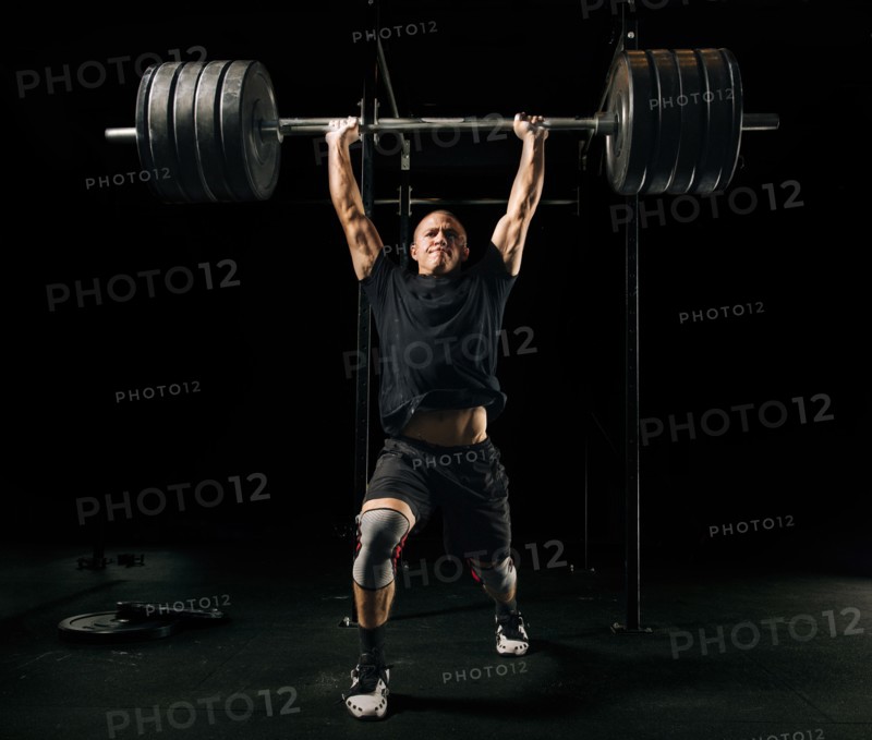 Man lifting heavy barbell in gymnasium