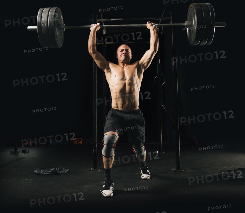 Man lifting heavy barbell in gymnasium