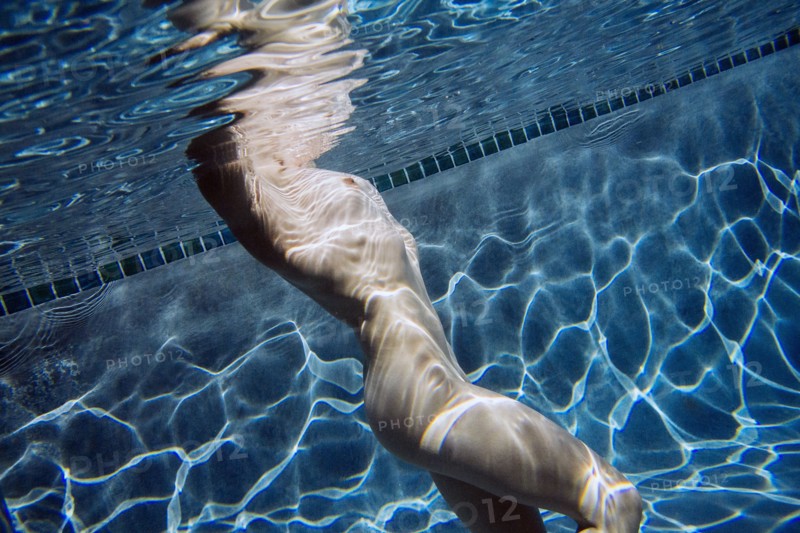 Naked Caucasian woman swimming underwater