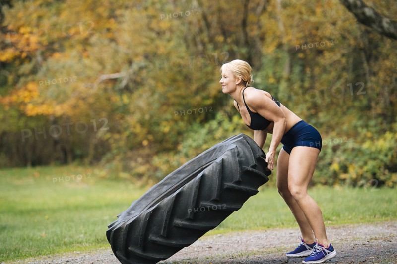 Caucasian woman lifting heavy tire in park