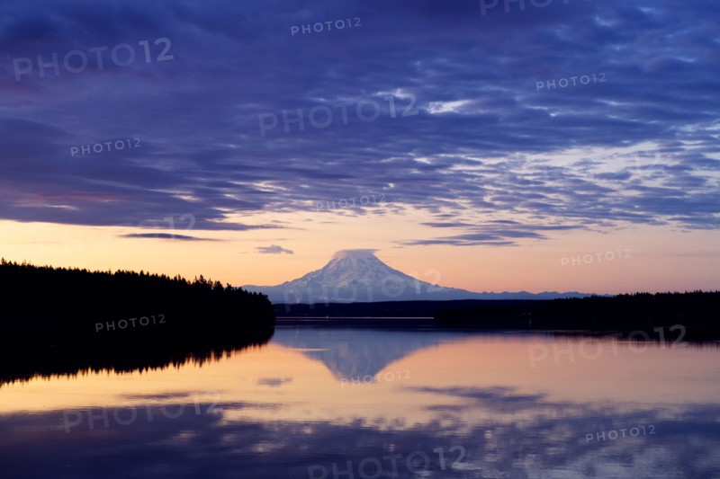 Reflection of clouds and mountain in river at sunset