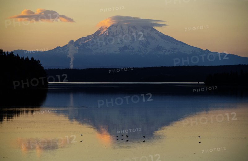 Reflection of clouds and mountain in river at sunset