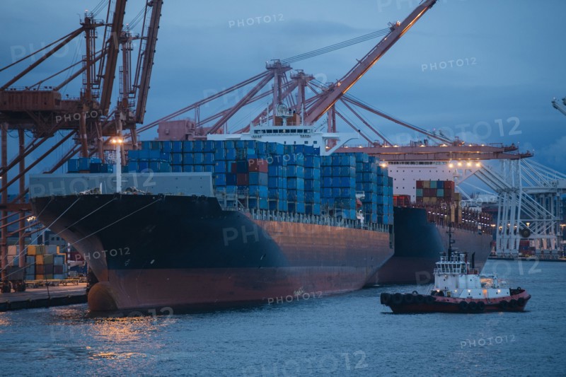 Cargo containers on freighter at shipping port near tugboat