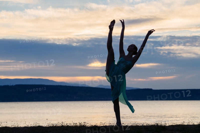 Caucasian ballerina dancing on beach at sunset