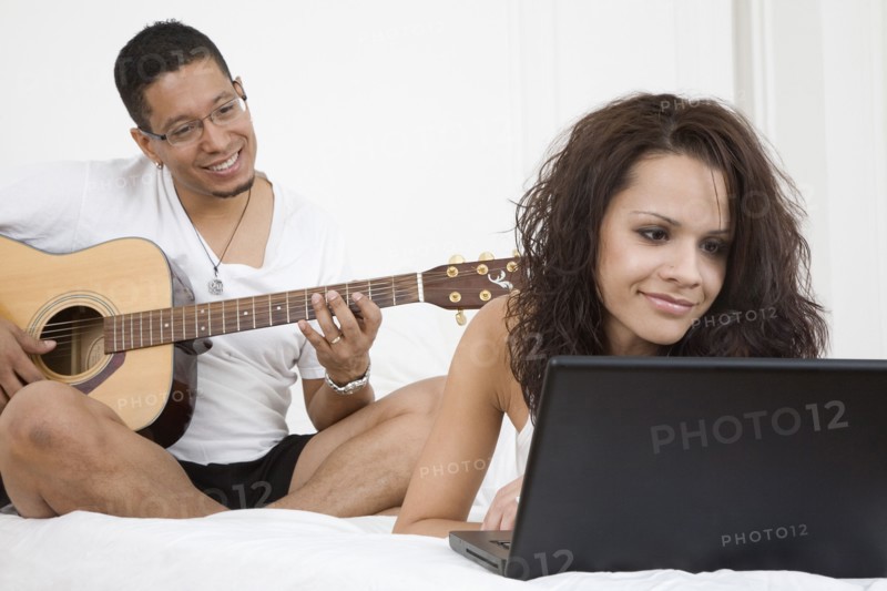 Hispanic couple relaxing on bed