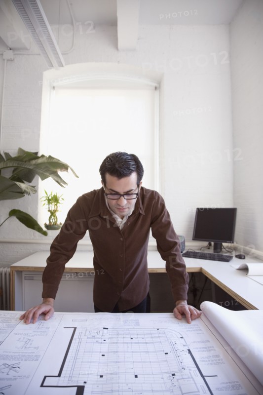 Hispanic businessman looking at blueprints