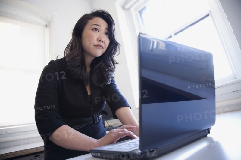 Asian businesswoman typing on laptop