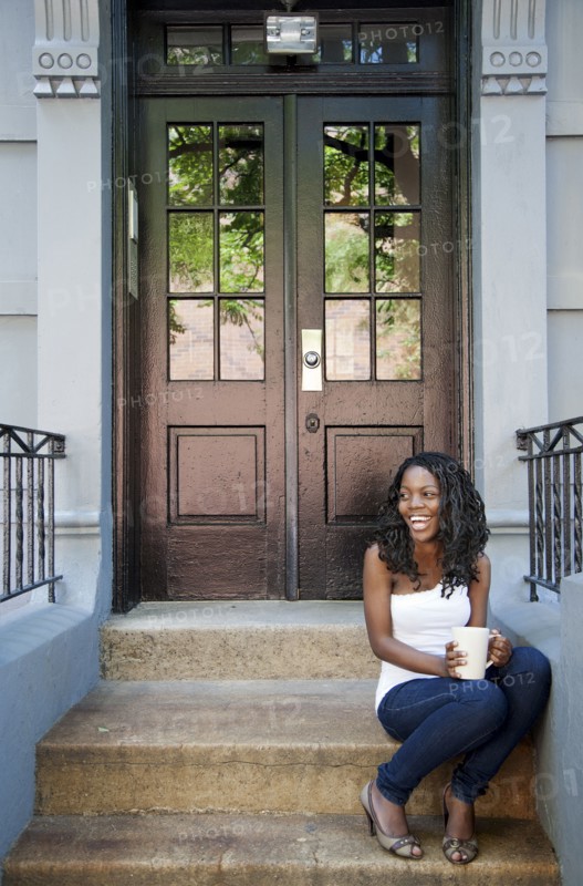 Black woman drinking coffee on front stoop