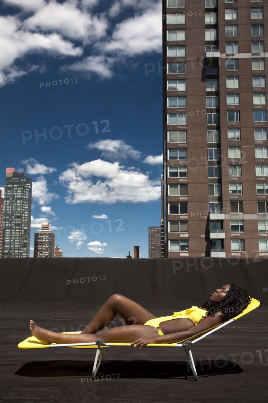 Black woman sunbathing on urban rooftop