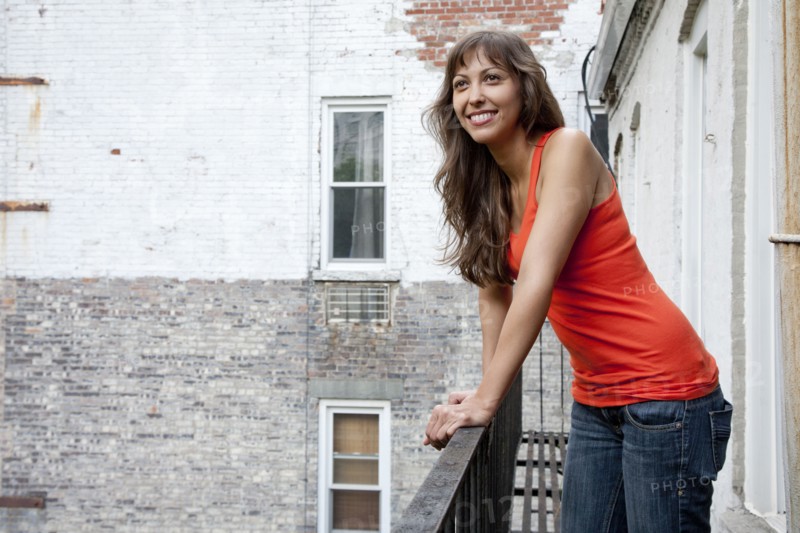 Mixed race woman leaning on fire escape railing