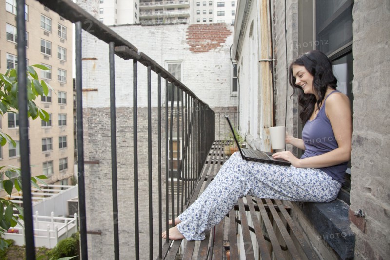 Woman using laptop on fire escape
