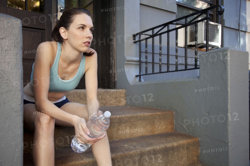 Caucasian woman relaxing with water bottle after exercise