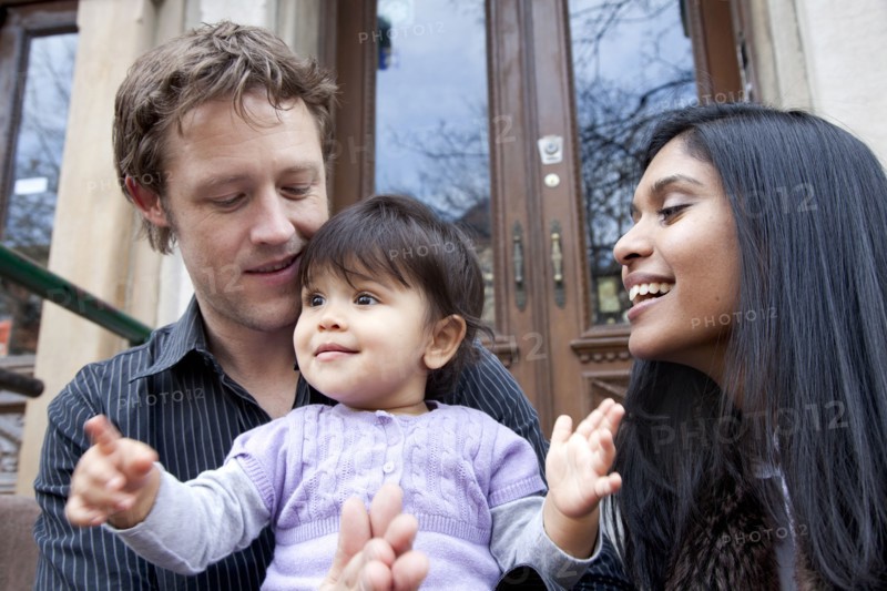 Parent's sitting on front stoop with baby girl