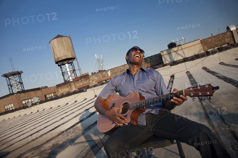 Black man playing guitar on rooftop