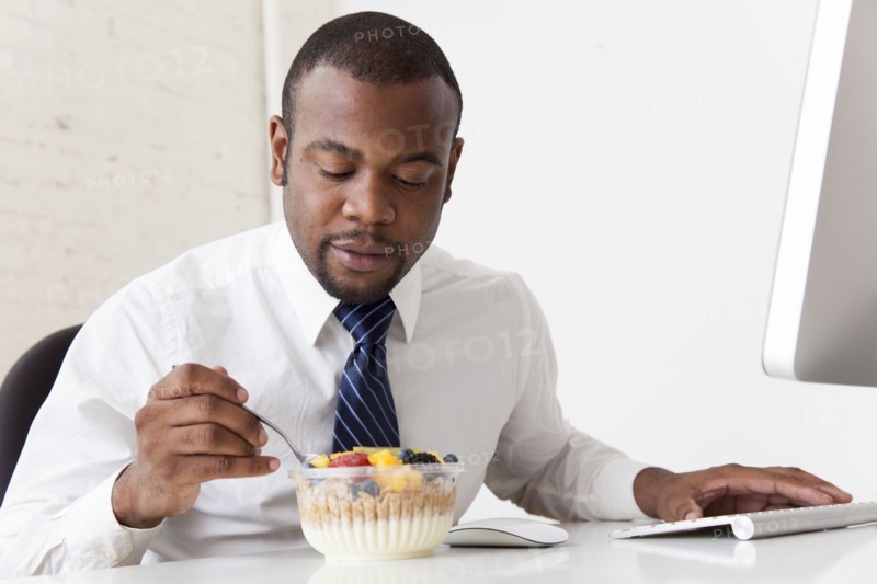 Black businessman eating breakfast at desk