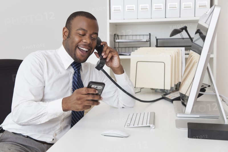 Black businessman using two telephones at one time