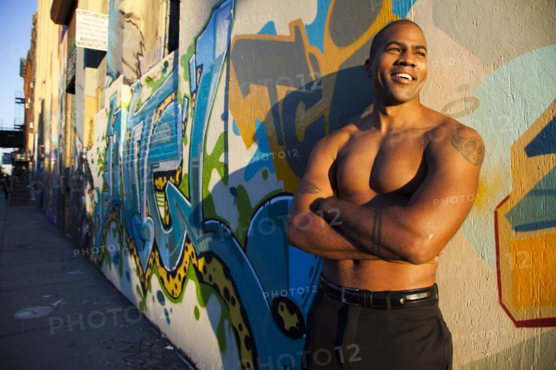 Bare chested African American man standing on city street