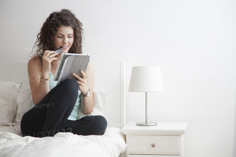 Caucasian woman using digital tablet in bed