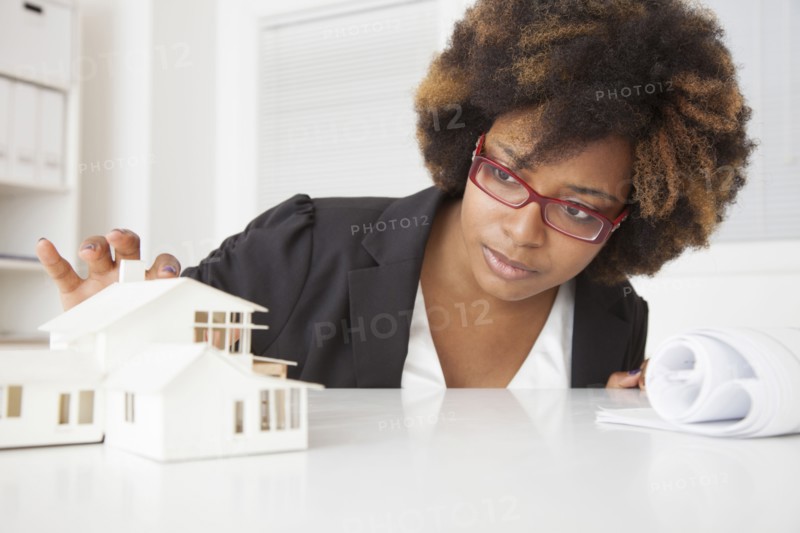 African American businesswoman working on model of house