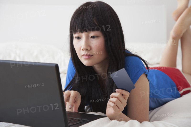 Chinese woman shopping online on bed