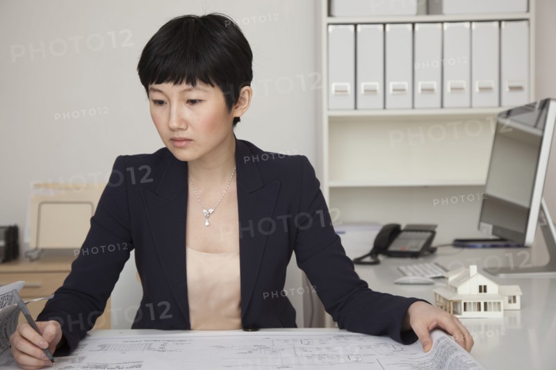 Businesswoman examining blueprints in office