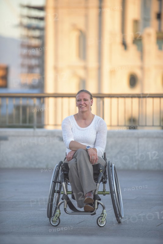 Disabled woman sitting in wheelchair on urban rooftop