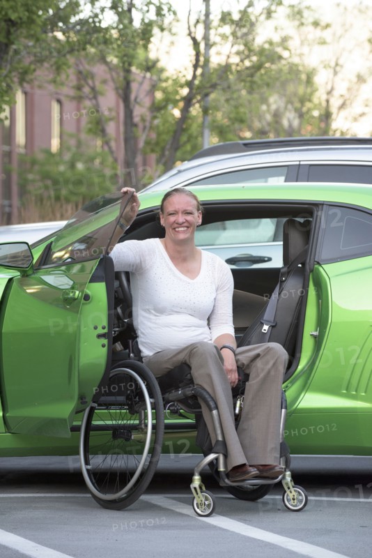 Disabled woman in wheelchair climbing into car