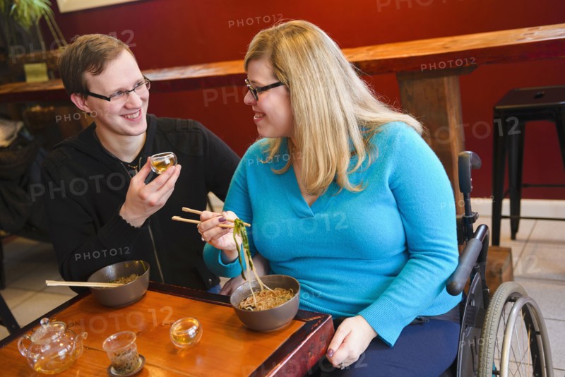 Paraplegic woman and boyfriend eating noodles in tea shop