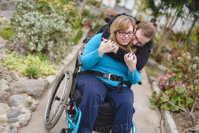 Man hugging paraplegic girlfriend in garden