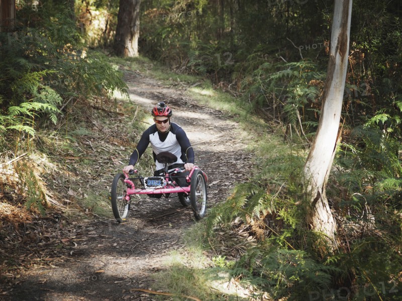 Man riding modified bicycles on forest path