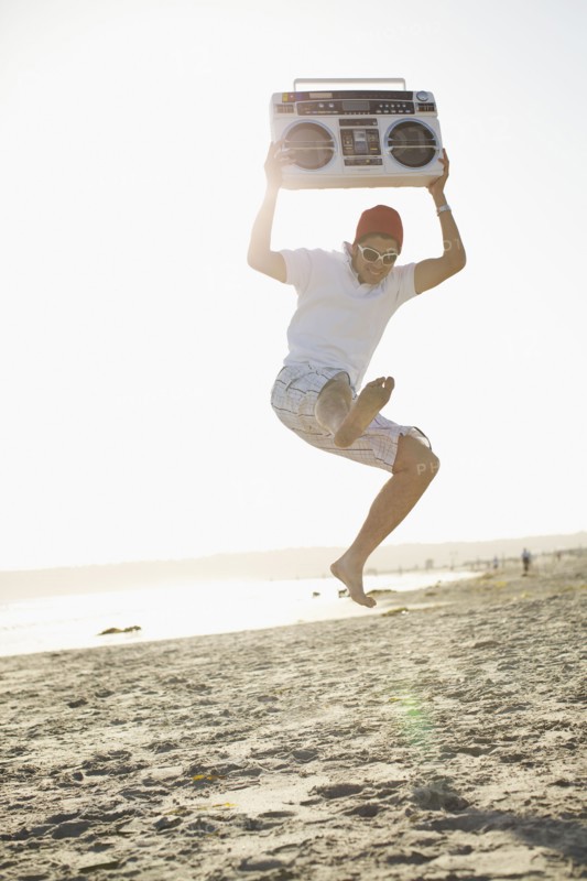 Hispanic man holding boom box and jumping