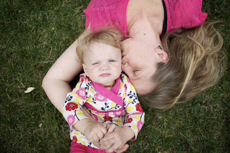 Caucasian mother and daughter laying in grass
