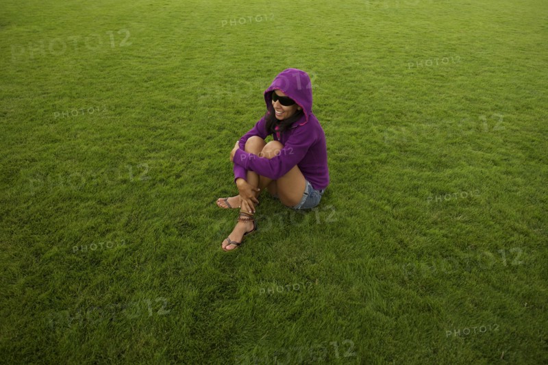 Smiling Hispanic woman sitting in grass