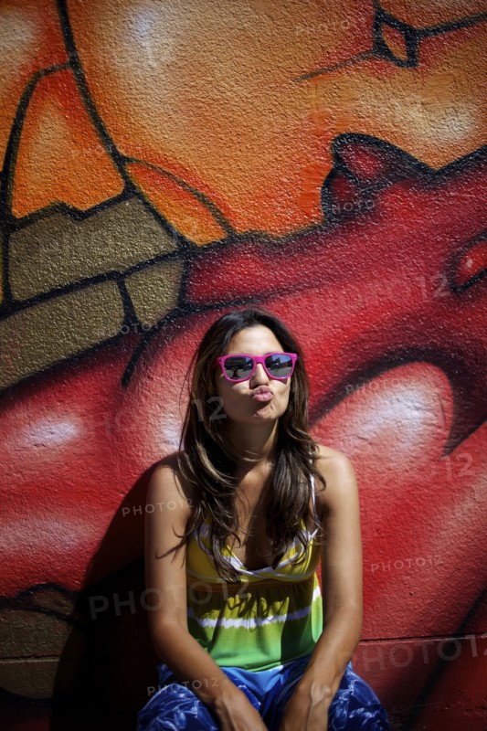 Hispanic woman standing near graffiti wall making face