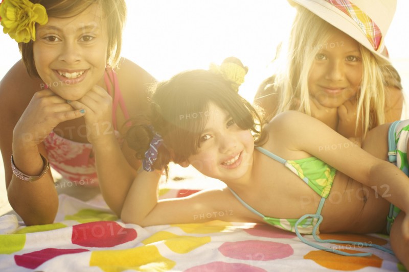 Children in bikinis laying on towel